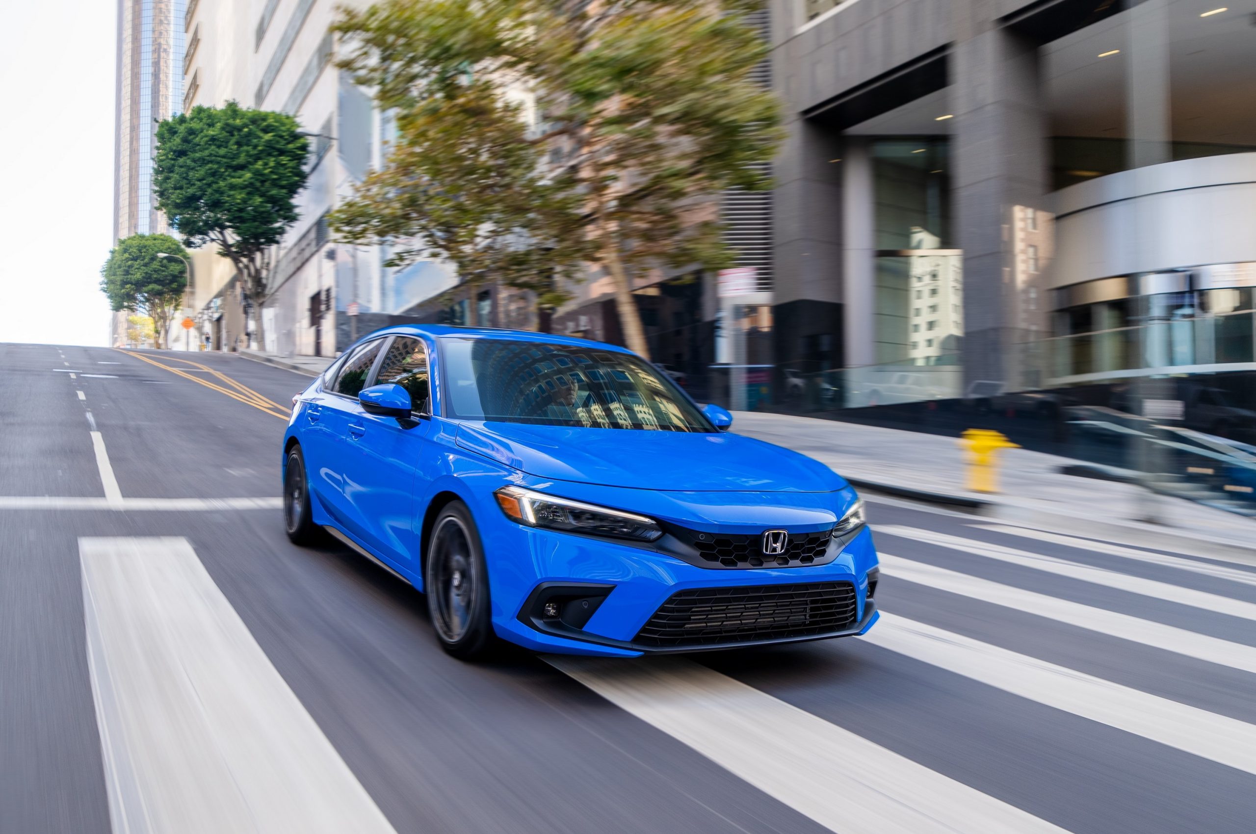 A blue 2022 Honda Civic hatchback shot from the front 3/4 on a city street