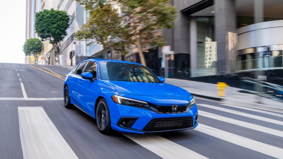 A blue 2022 Honda Civic hatchback shot from the front 3/4 on a city street