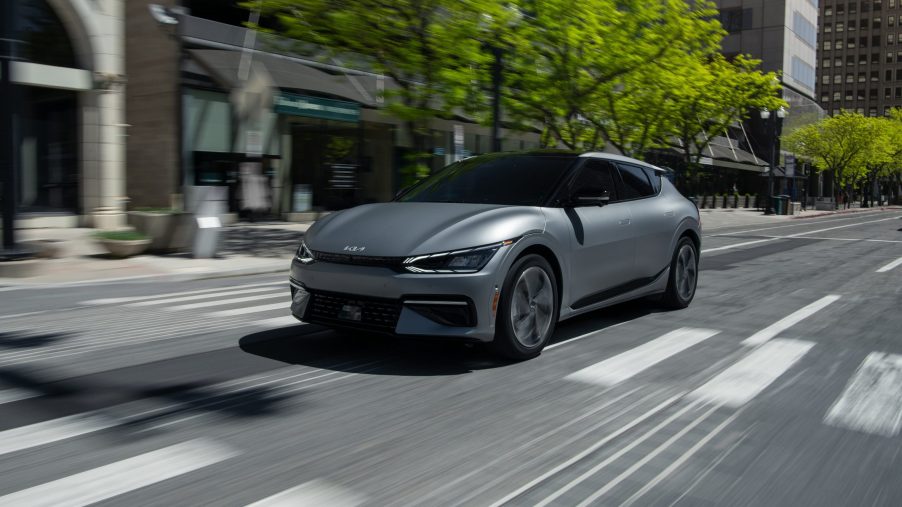 A silver 2022 Kia EV6 rolls down a city street, shot from the 3/4 angle