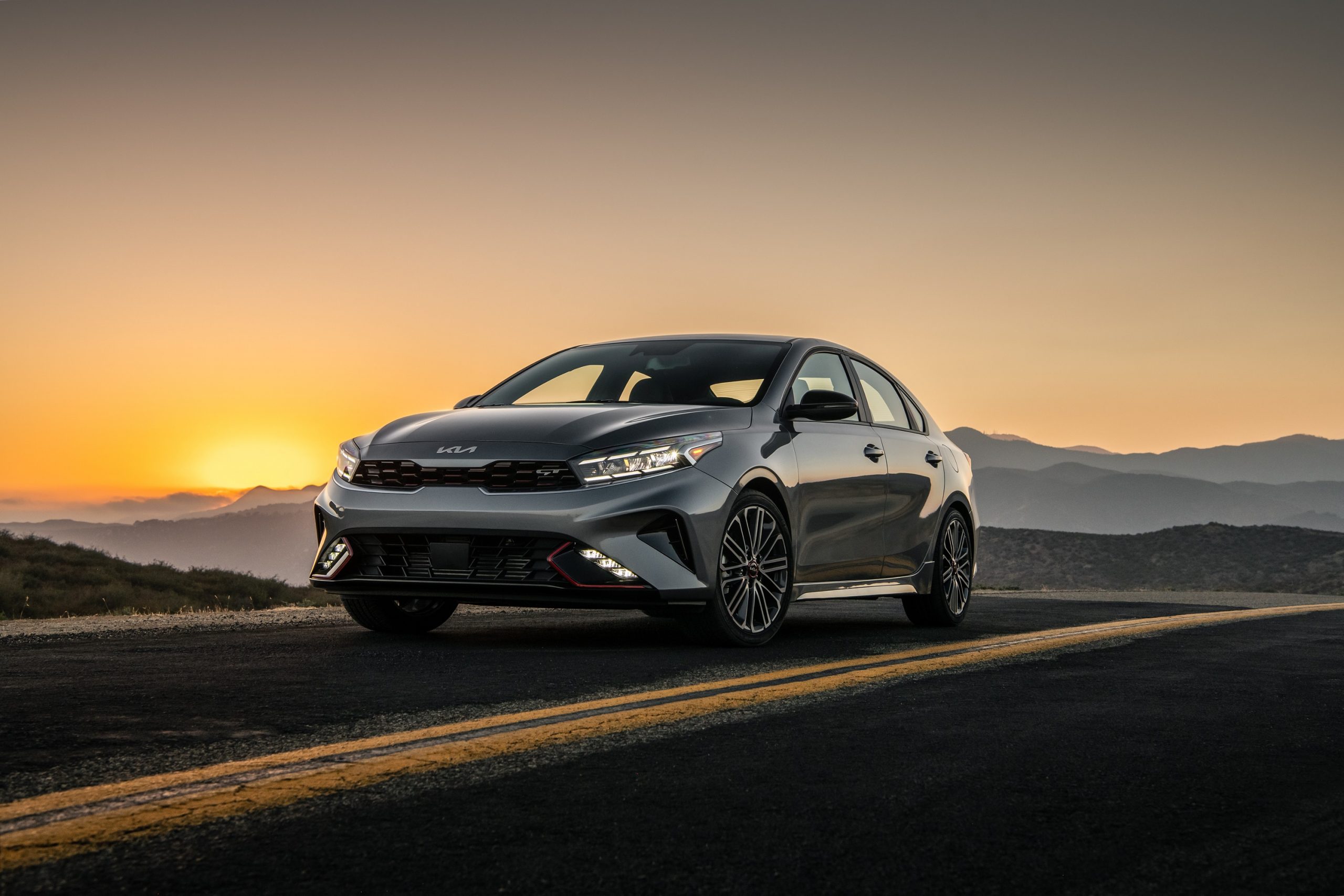 The 2022 Kia Forte GT shot at sunset on a mountain road from the front 3/4 angle