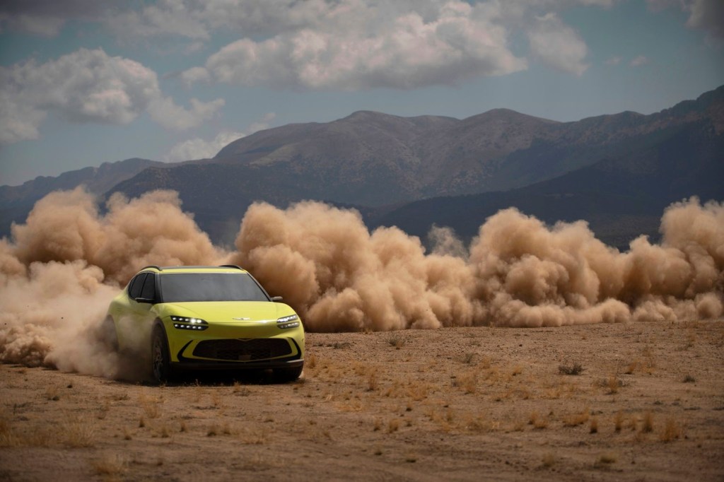 A yellow-green 2023 Genesis GV60 drives through the dirt