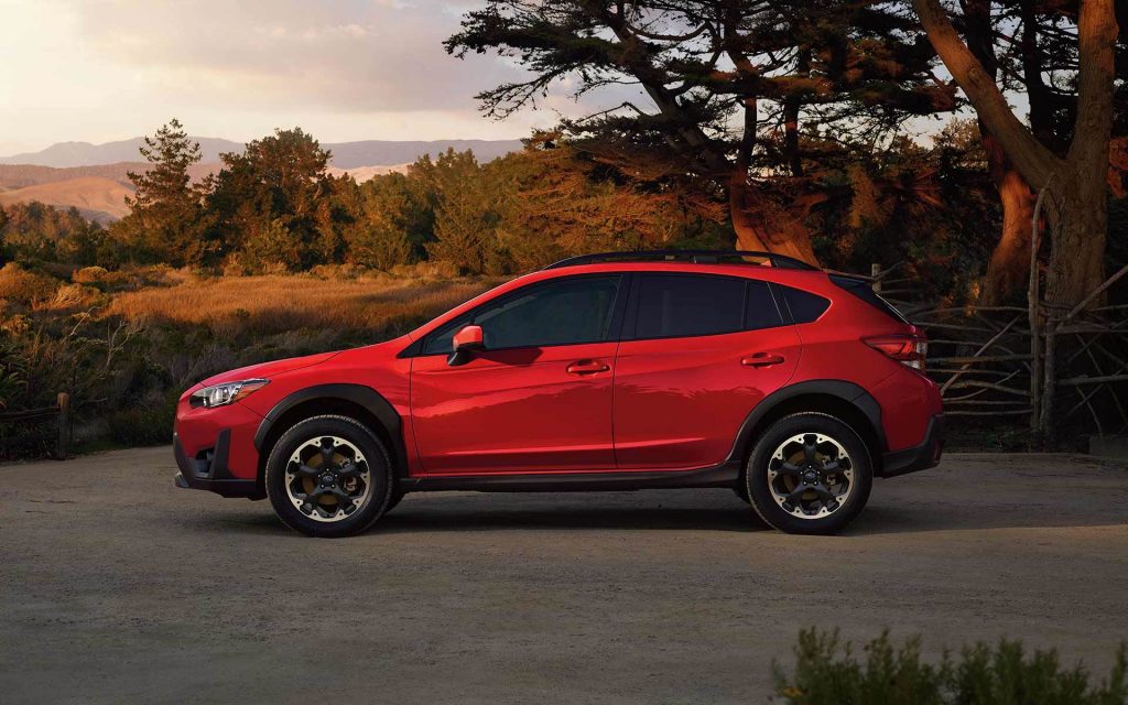 A red 2021 Subaru Crosstrek parked in front of mountains at sunset.
