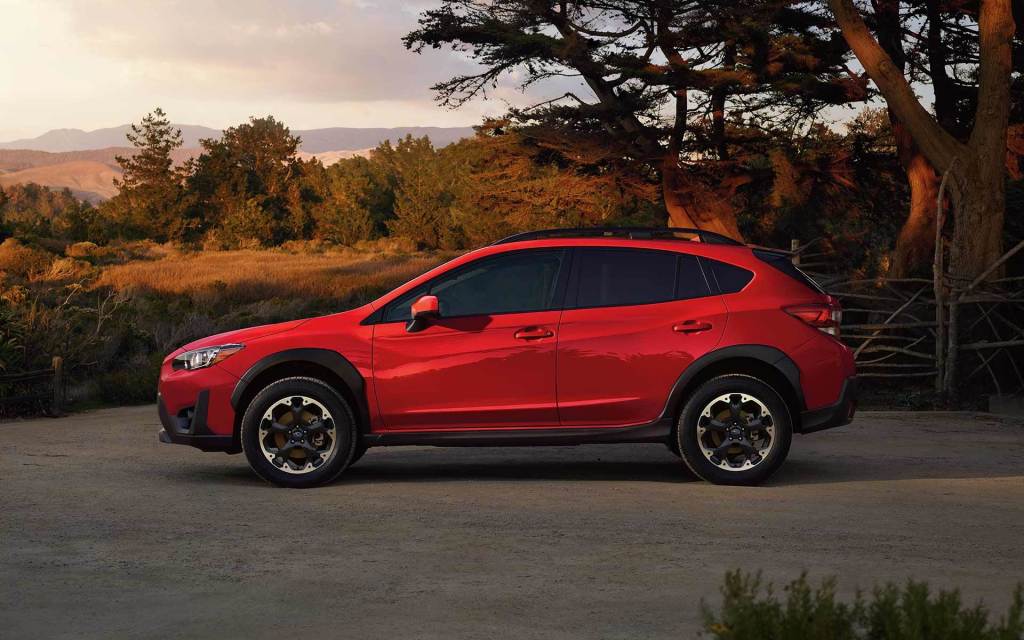 A red 2021 Subaru Crosstrek parked in front of mountains at sunset.