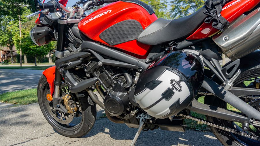 A black-and-white Bell motorcycle helmet locked to a red 2012 Triumph Street Triple R with a Kuryakyn lock
