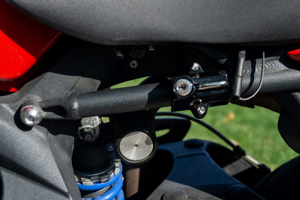 A black Kuryakyn motorcycle helmet lock attached to a red and black 2012 Triumph Street Triple R