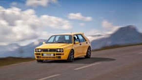 A yellow Lancia Delta Integrale drives through the French Alps