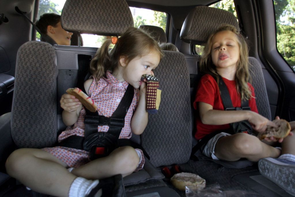 Children backseat of a car making a bad smell expression