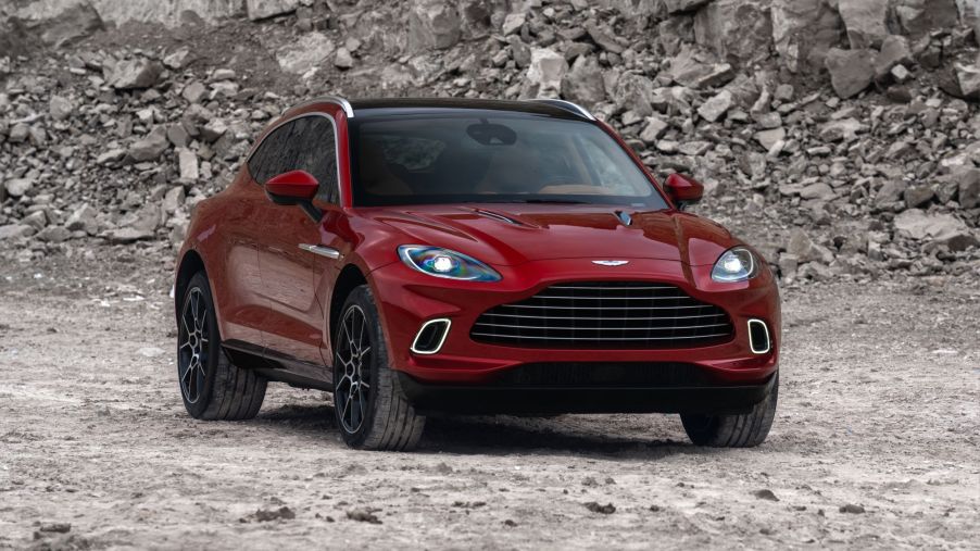 A red Aston Martin DBX in a rocky area on dirt.