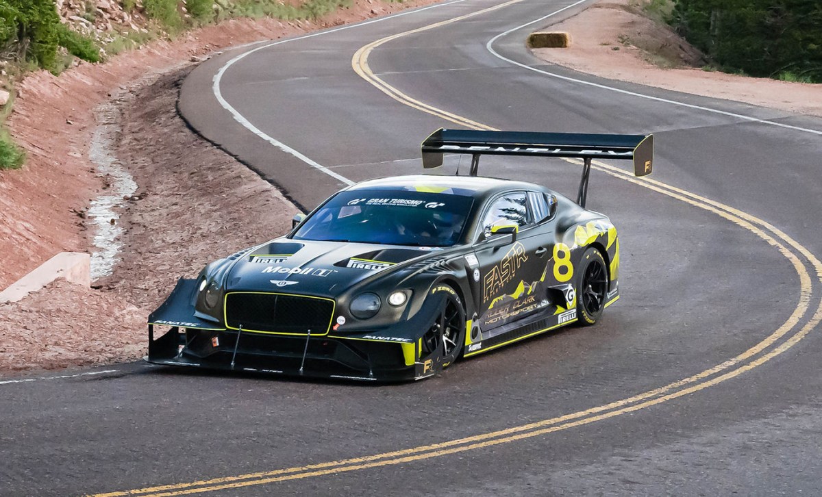 Bentley GT3 Pikes Peak race car seen driving up a mountain road. The same race car is seen in the drag race video featured in this article.