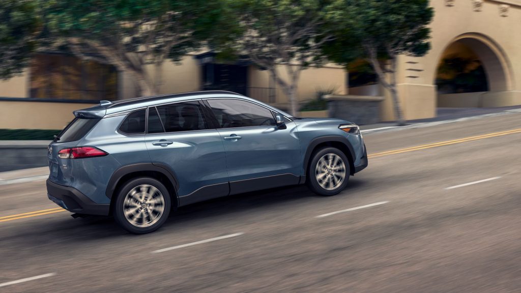 Blue 2022 Toyota Corolla Cross driving up a hill, it's losing to the 2022 Hyundai Kona