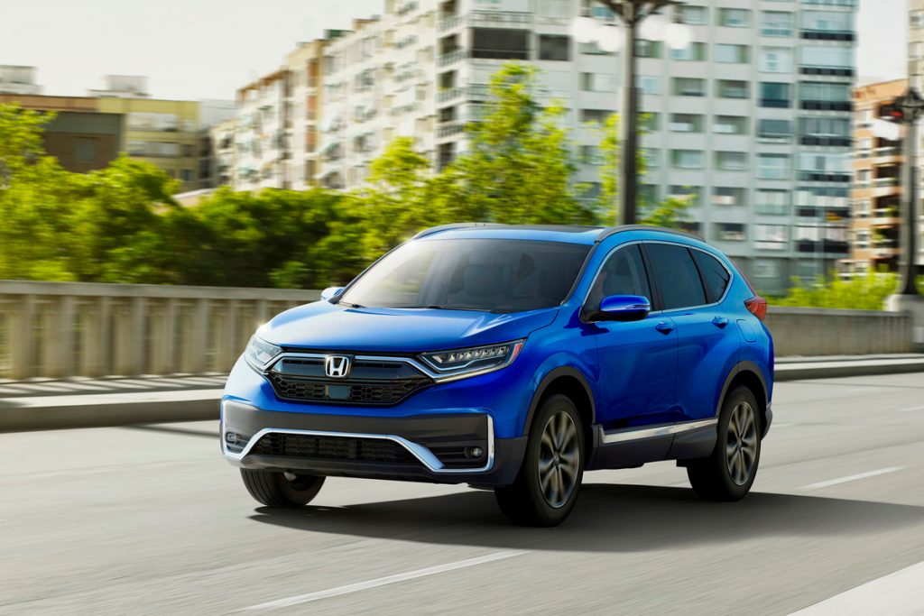 Blue Honda CR-V driving by large buildings