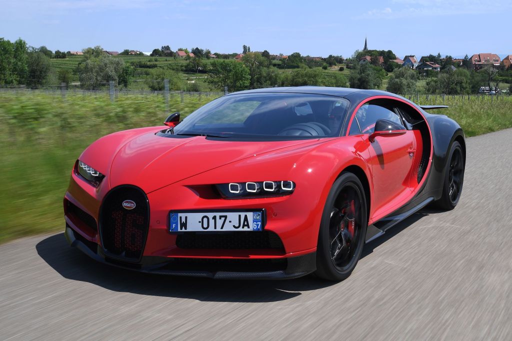 Red Bugatti Chiron parked next to a field