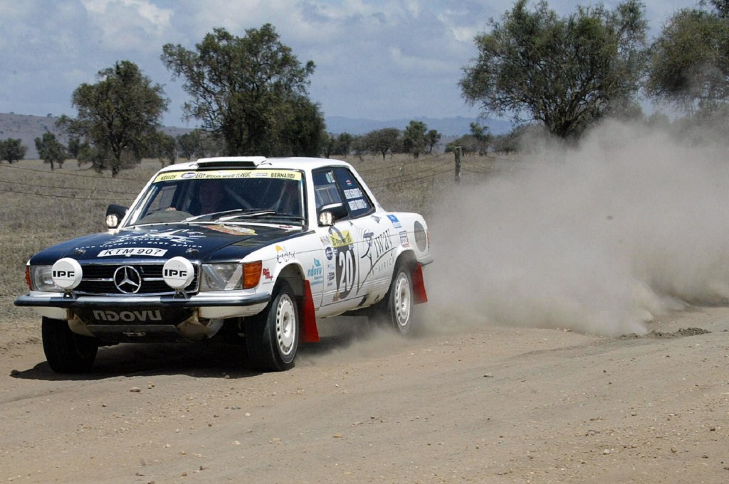 A liveried white-and-black C107 Mercedes 450 SLC drives through the sand at the 2005 East-Africa Rally