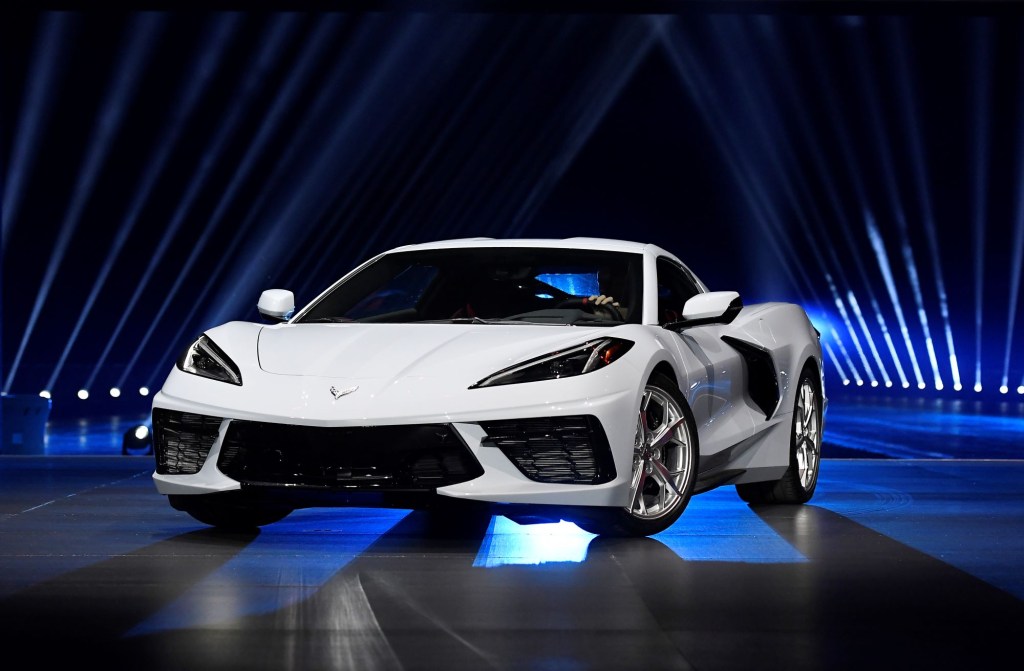 A white C8 Corvette Stingray in front of a black background with blue lights.