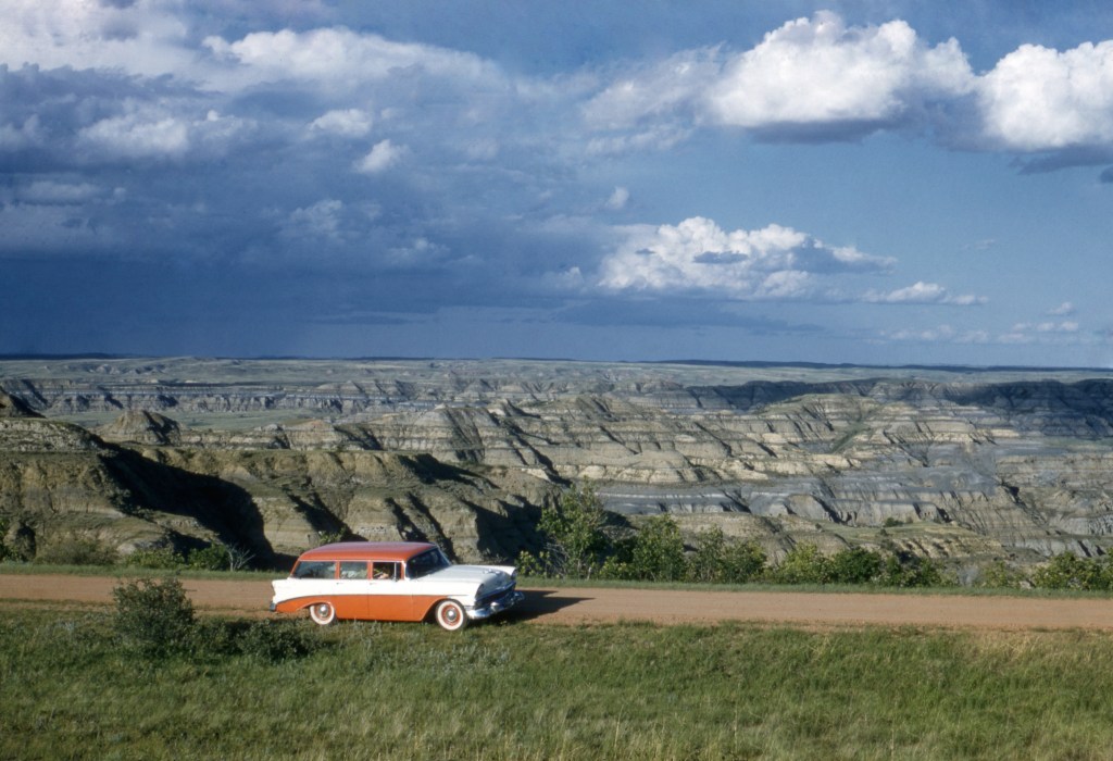 Classic Car Driving Down Dirt Road On Road Trip
