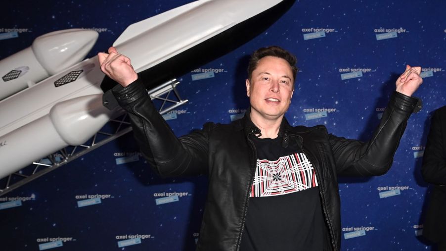 Elon Musk standing in front of a model of a rocket