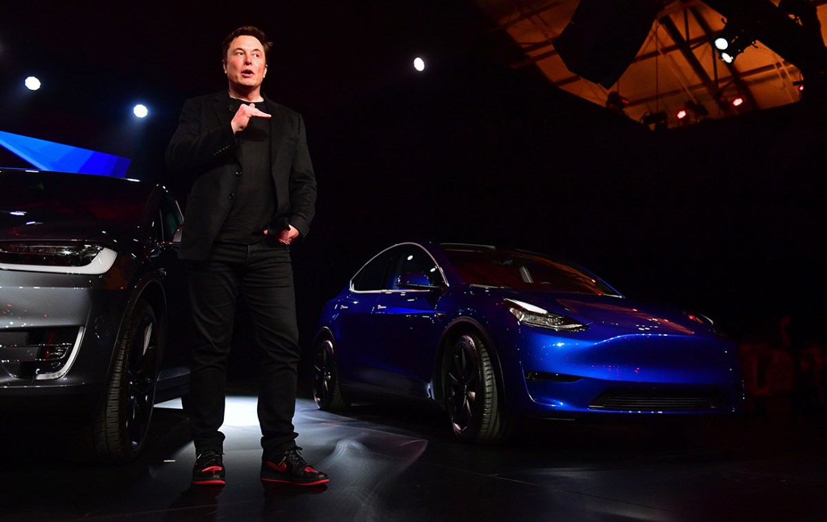 Elon Musk standing next to a Tesla Model Y during a presentation