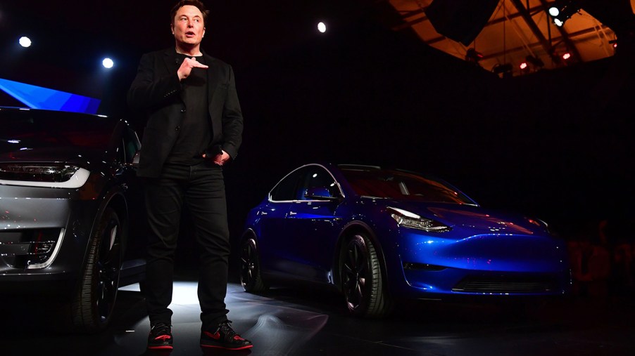 Elon Musk standing next to a Tesla Model Y during a presentation
