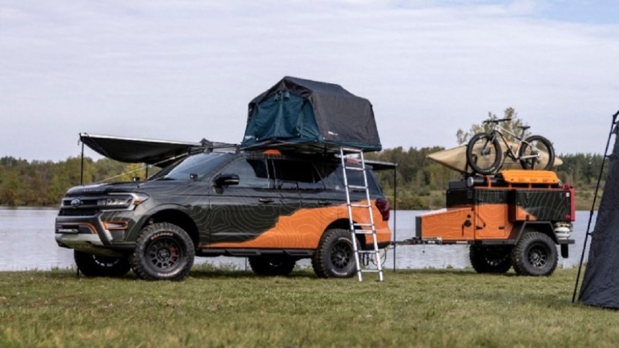 A dark green and orange 2022 Ford Expedition Timberline Off-Grid pulling a trailer, with a kayak on top.