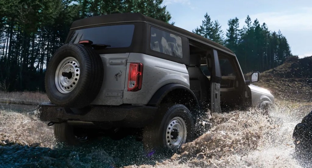 A gray Ford Bronco is driving through water.