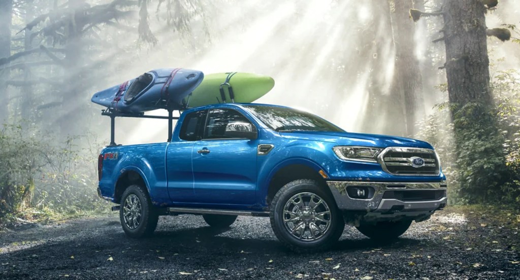 A blue Ford Maverick is parked in nature carrying kayaks. 