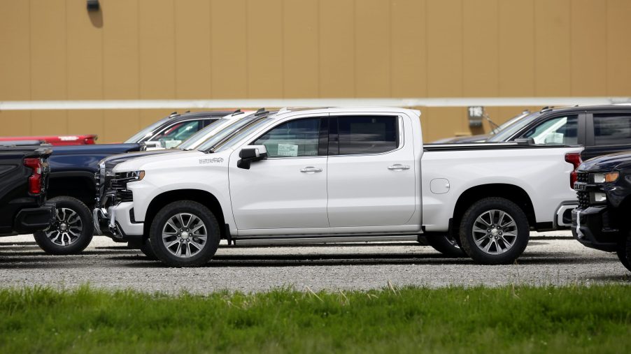 A white 2019 GMC Sierra 1500 parked among a sea of Sierra 1500 and Chevy Silverado models. We recommend buying this model year used.