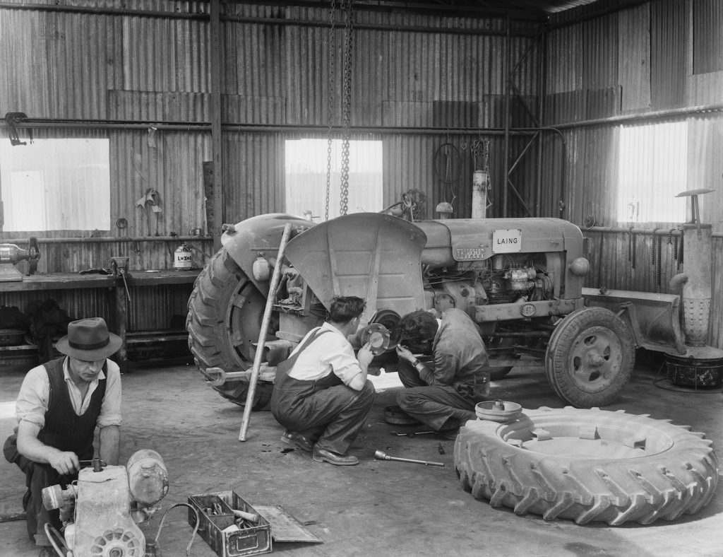 A 1959 photo of two Laing workers carrying out maintenance work on the rear right wheel of a Fordson Major Diesel Tractor. | Hulton Archive/Getty Images