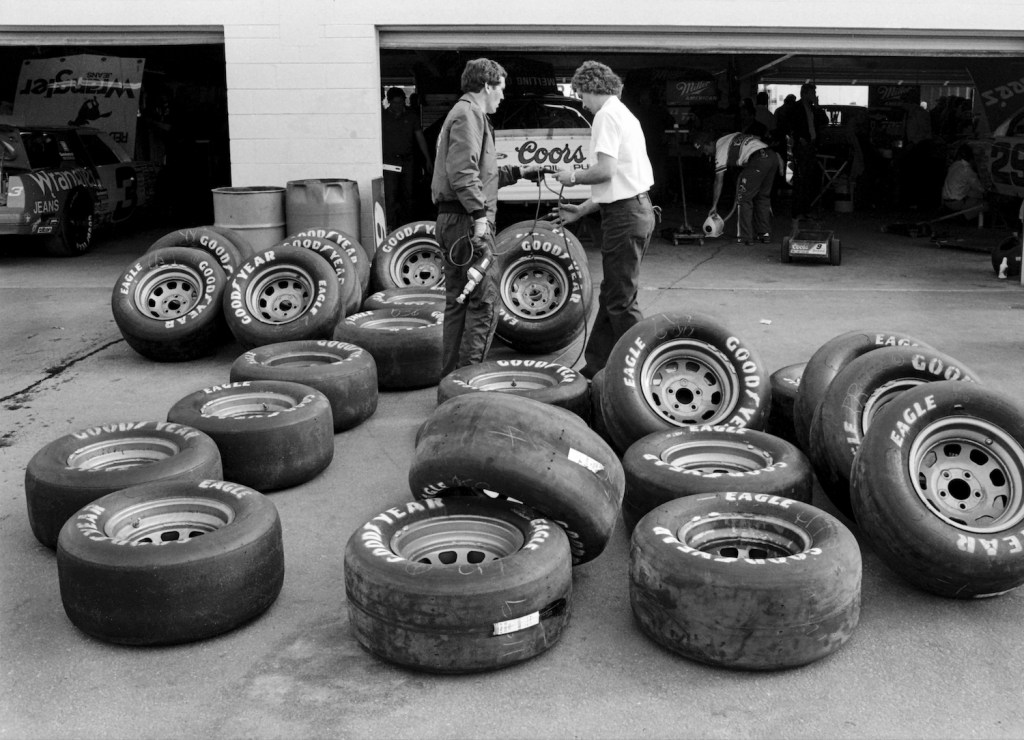 This is a photo of members of Bill Elliott's NASCAR pit crew prepare racing tires before the 1987 Daytona 500 race at Daytona International Speedway in Daytona Beach, Florida. | Robert Alexander/Getty Images