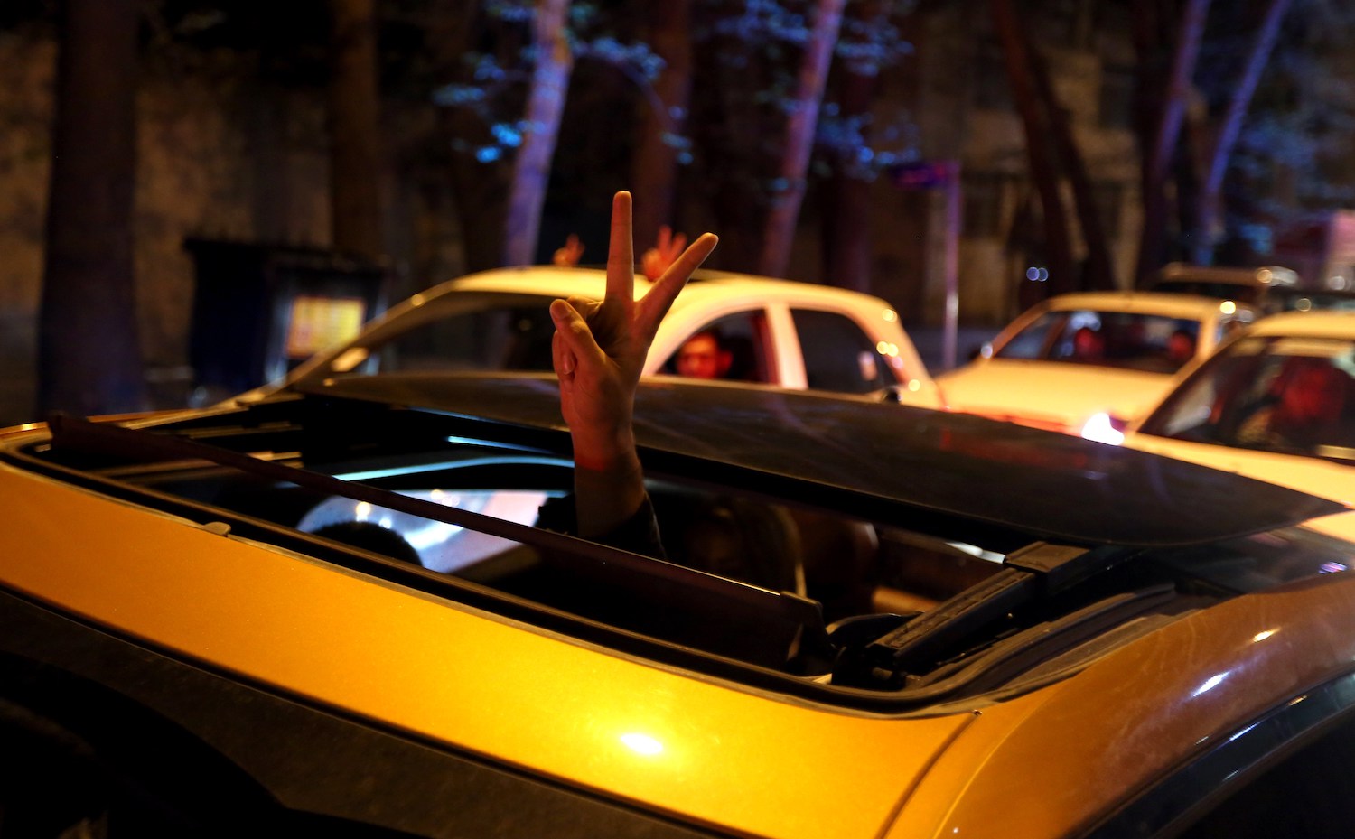Laws about who must wear a shirt in public vary by state. This is a photo of a person sticking their hand out of a sunroof in Iran. | ATTA KENARE/AFP via Getty Images