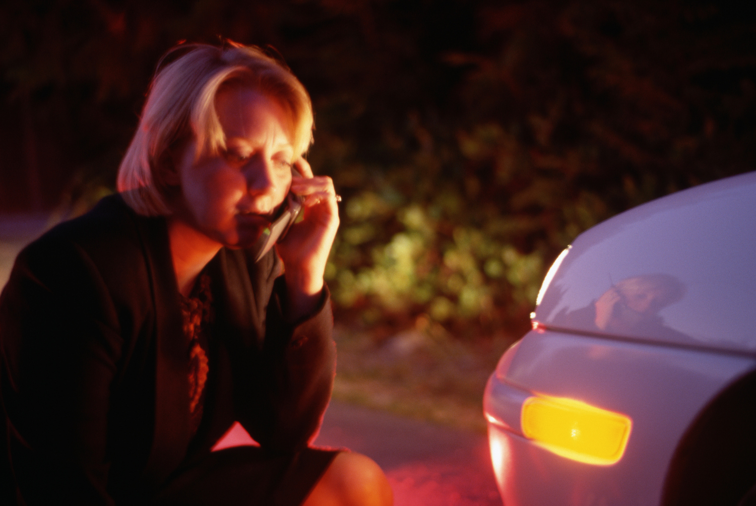 This is a photo of a woman examining the front of her sedan and calling for help. 466,000 Sonata sedans are at risk of a turn signal malfunction and affected by Hyundai recall. Doug Wilson/CORBIS/Corbis via Getty Images