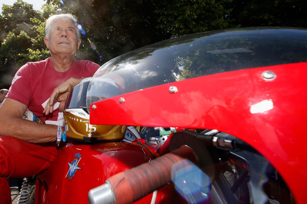 Giacomo Agostini in a red racing suit sitting on a vintage red MV Agusta race bike at the 2015 Goodwood Festival of Speed