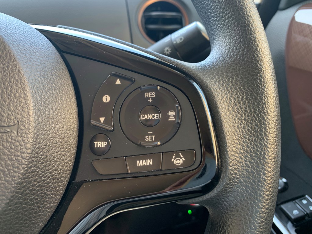 A Honda steering wheel that shows the driver-assist buttons for adaptive cruise control and lane-keep assist. 
