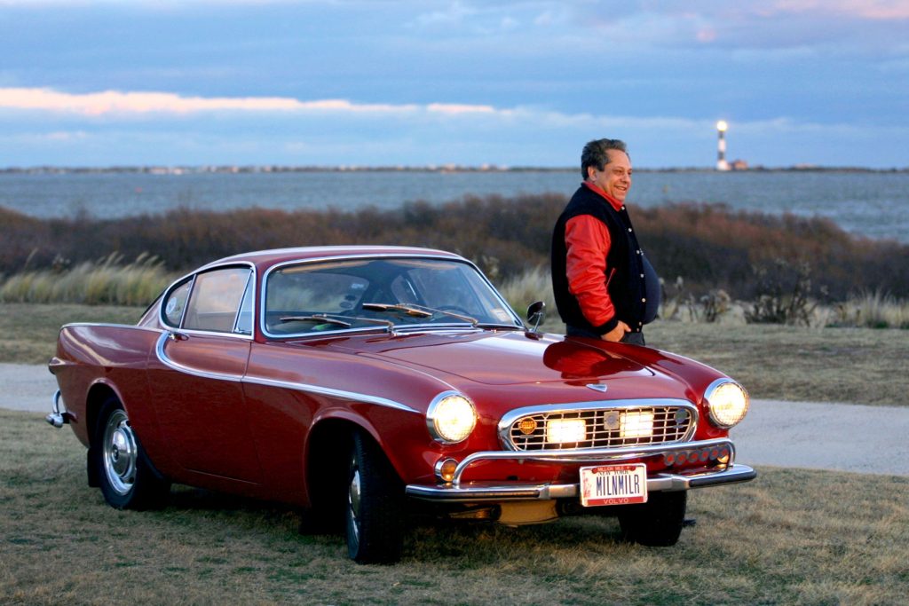 Irv Gordon and his record-holding red 1966 Volvo P1800 next to the ocean
