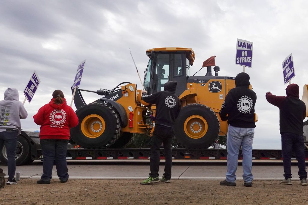 A truck hauls a piece of John Deere equipment from the factory past workers picketing outside of the John Deere. John Deere Strike: Workers Strike Over Contract. A truck hauls a piece of John Deere equipment from the factory past workers picketing outside of the John Deere