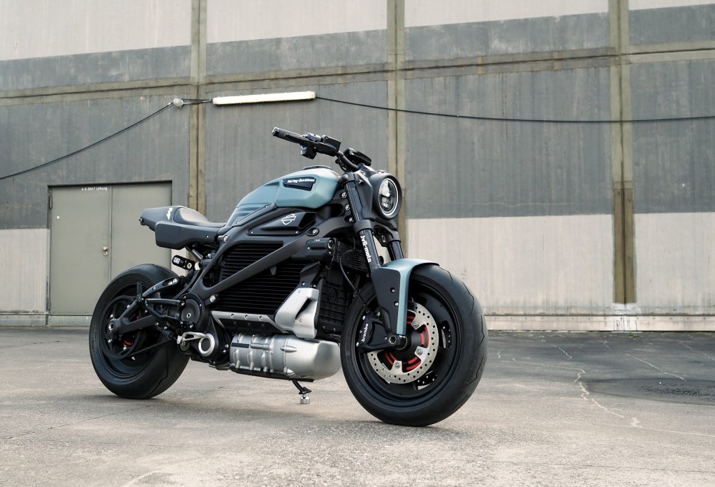 The blue-and-black JvB Moto 'Silent Alarm' custom 2020 Harley-Davidson LiveWire next to an industrial garage