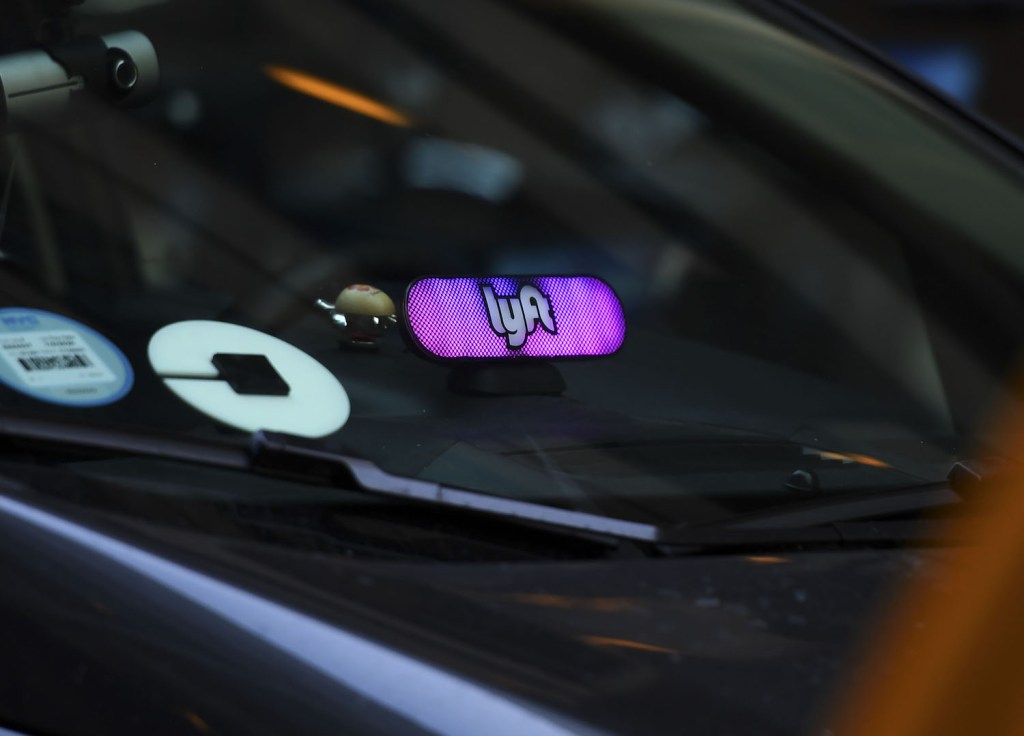 This is a photo of rideshare badges on a car. The Lyft and Uber safety teams are adding safety features. | TIMOTHY A. CLARY/AFP via Getty Images