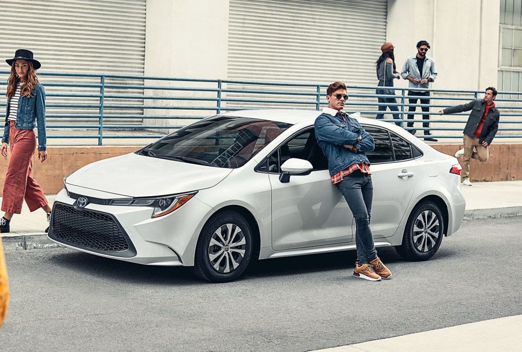 Man leaning up against a white 2022 Toyota Corolla to represent a car selling scam