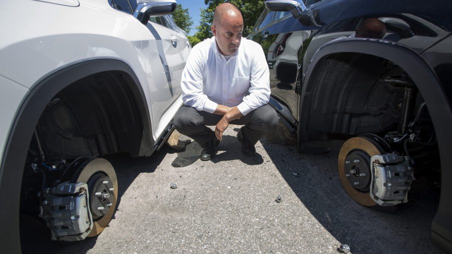 a man staring at two car at a dealership with missing wheels. Is the TikTok "lug nut challenge" real or just halloween hysteria?