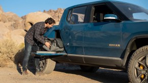 Man placing a bag in the gear tunnel of a blue Rivian R1T