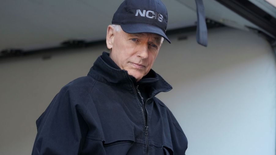 Mark Harmon from NCIS wearing a black hat and black jacket in a white room.