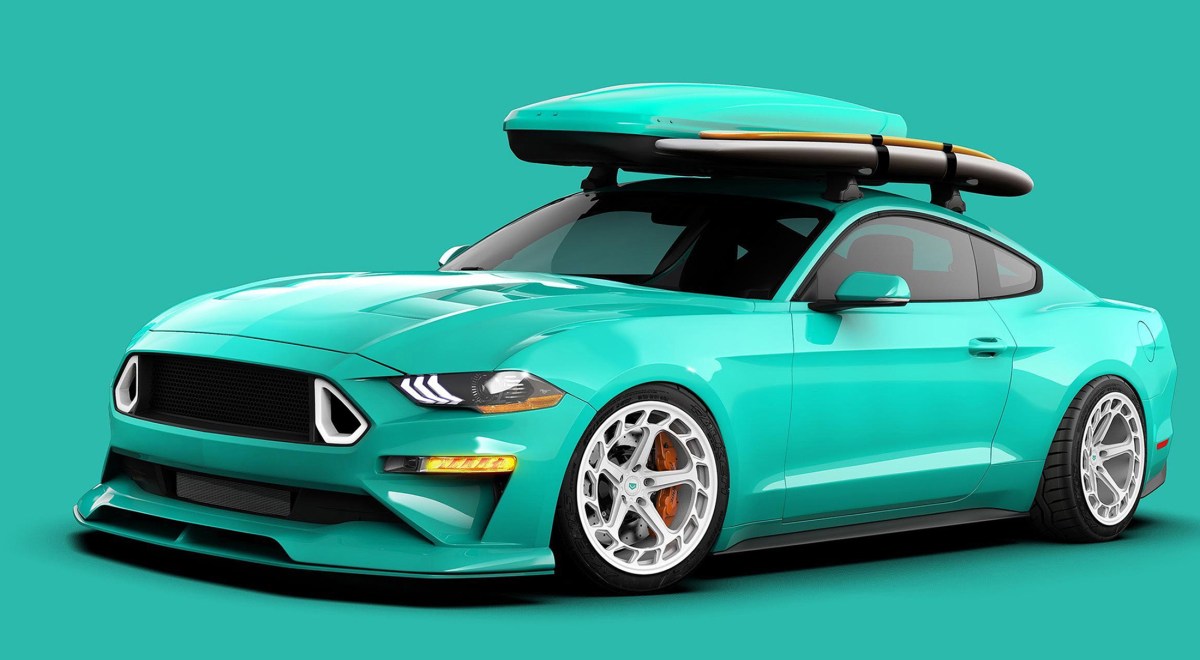 A teal painted 2021 Ford Mustang EcoBoost built by Gene Tjin. The Mustang is lowered and has white five-spoke wheels. On top of the car is a roof rack which holds a surfboard and a color-matched teal storage container. This car will be on display at SEMA 2021