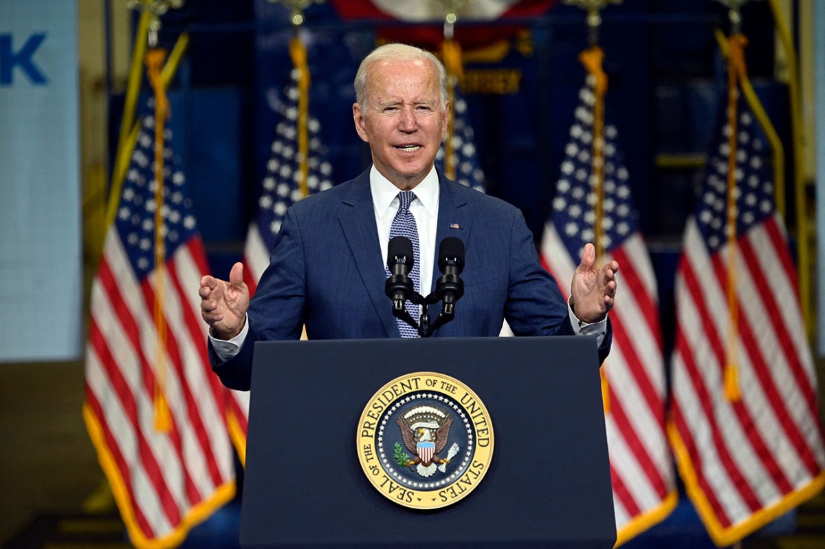 President Joe Biden giving a speech at a Presidential podium with four American flags behind him