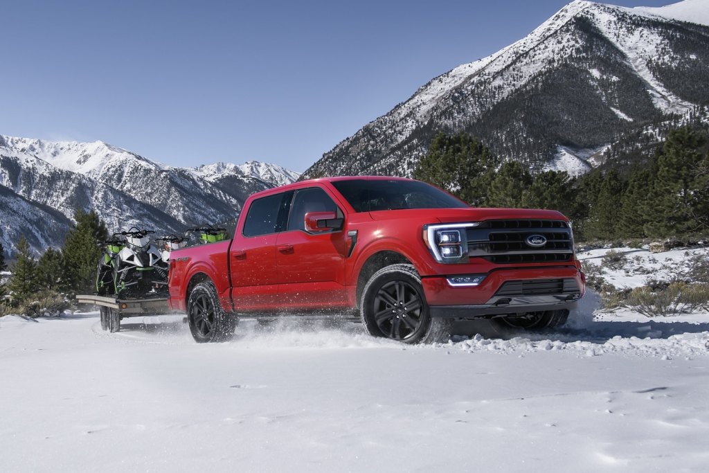 Red 2022 Ford F-150 towing some snowmobiles for a comparison with the 2022 GMC Sierra 1500