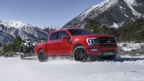 Red 2022 Ford F-150 towing some snowmobiles for a comparison with the 2022 GMC Sierra 1500