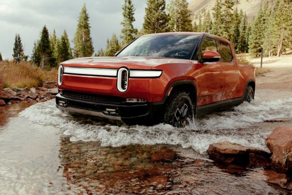 Red 2022 Rivian R1T driving through water
