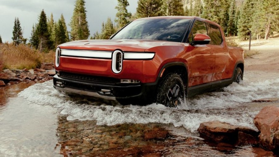 Red 2022 Rivian R1T driving through water