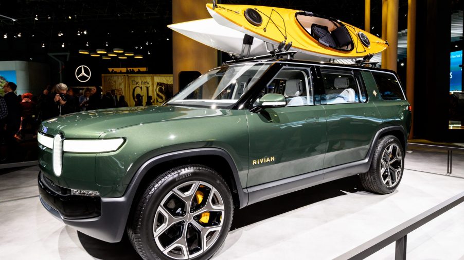 A green Rivian R1S with canoes on top