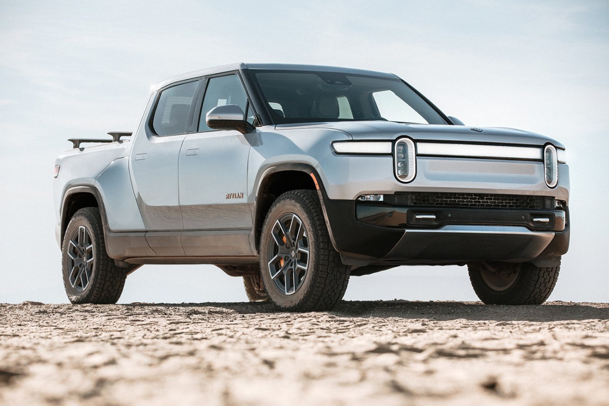 Rivian R1T electric truck in silver, parked on hill crest with dirt on tires