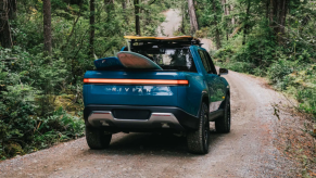 The Rivian R1T electric truck in blue driving on a forest trail