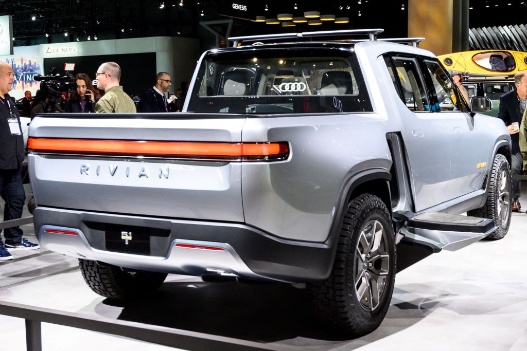 A silver Rivian R1T sitting on a white pad indoors.